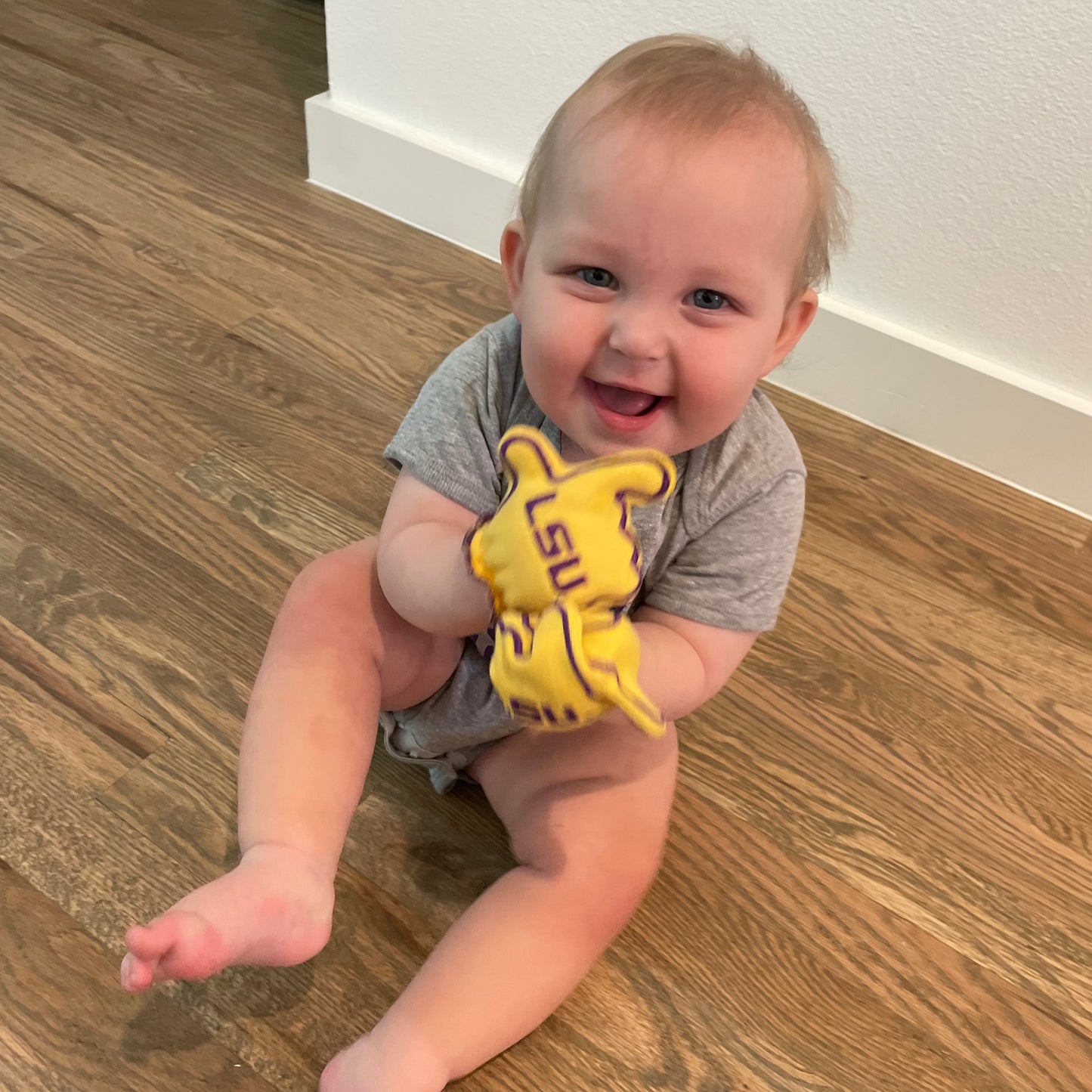 Baby wearing LSU Geaux Tigers baby mittens in gold