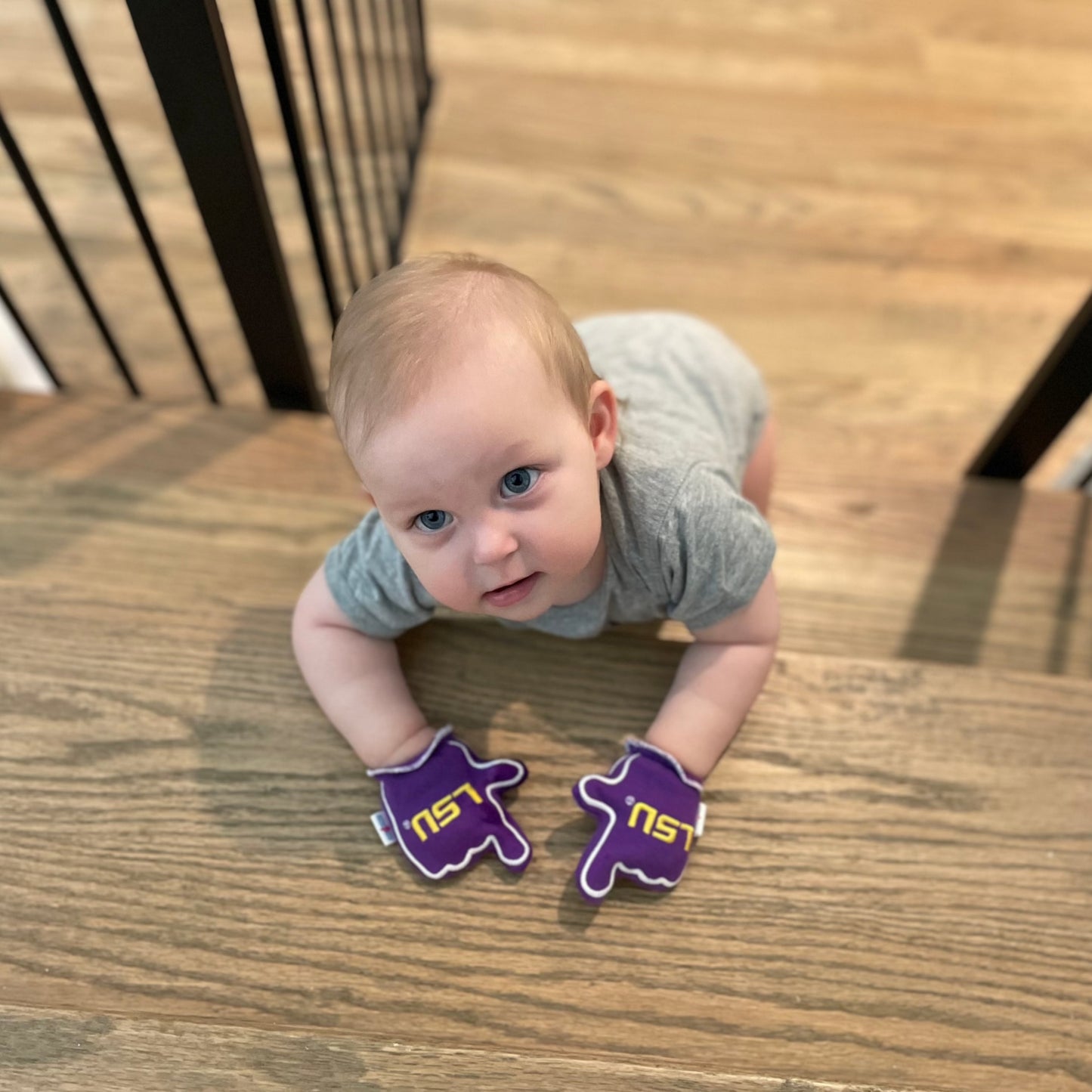 Baby wearing LSU Geaux Tigers baby mittens in purple