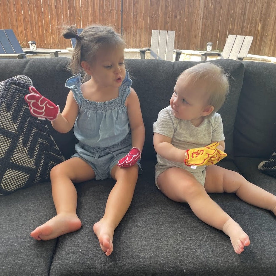 Two infants wearing USC V for Victory baby mittens in red and gold