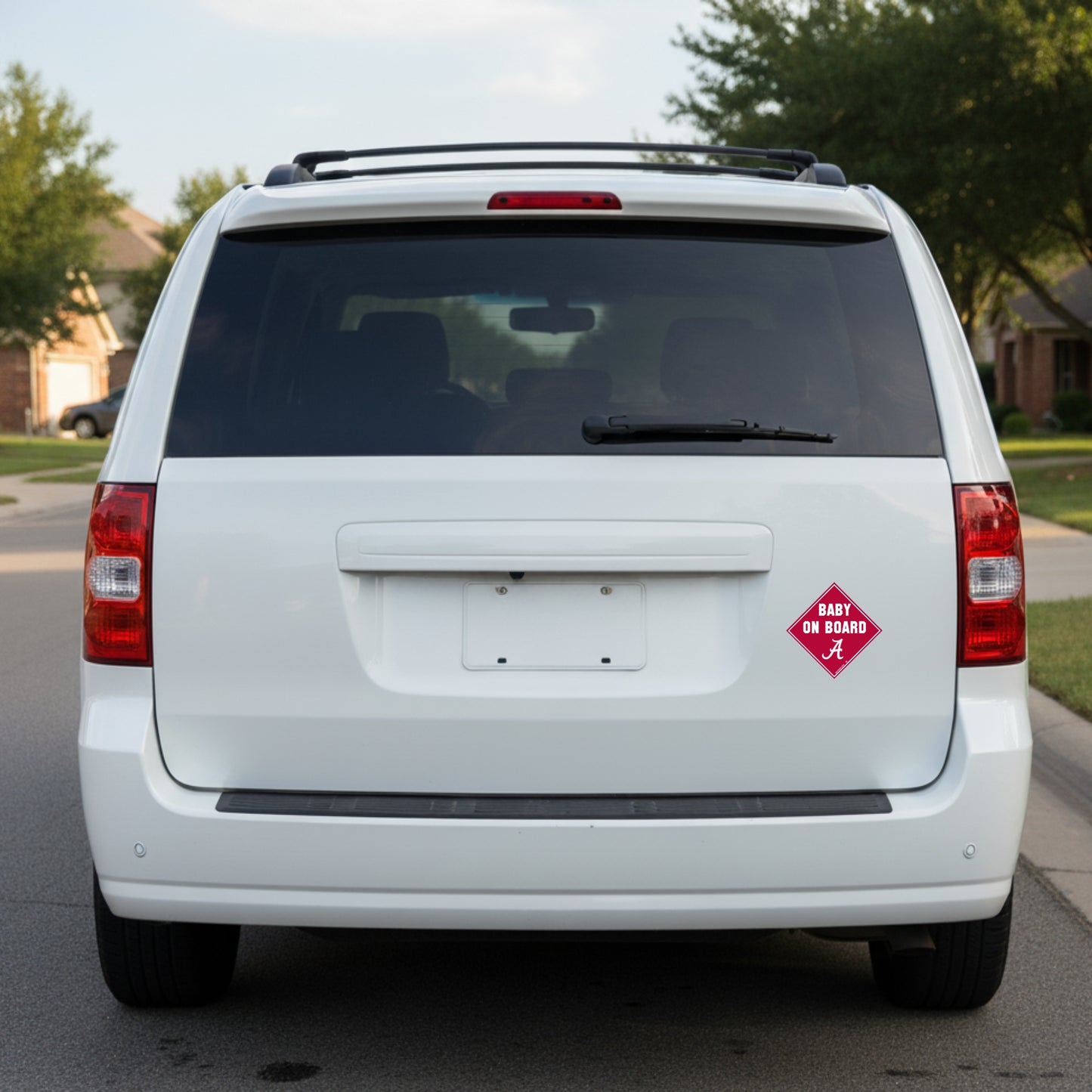 White van with a 'Baby on Board' sign with Alabama logo on the back, parked on a street.