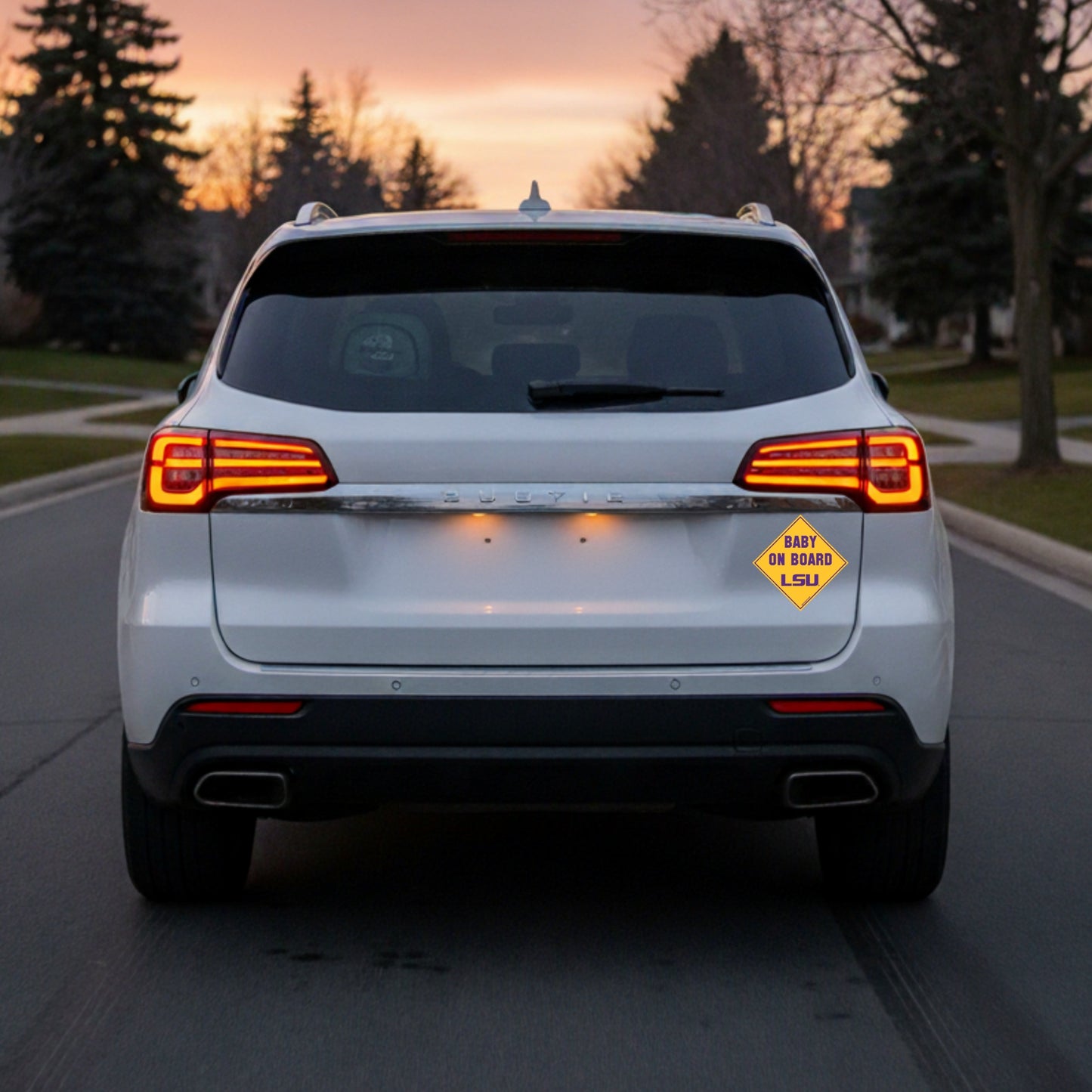 White SUV with 'Baby on Board' sign at sunset