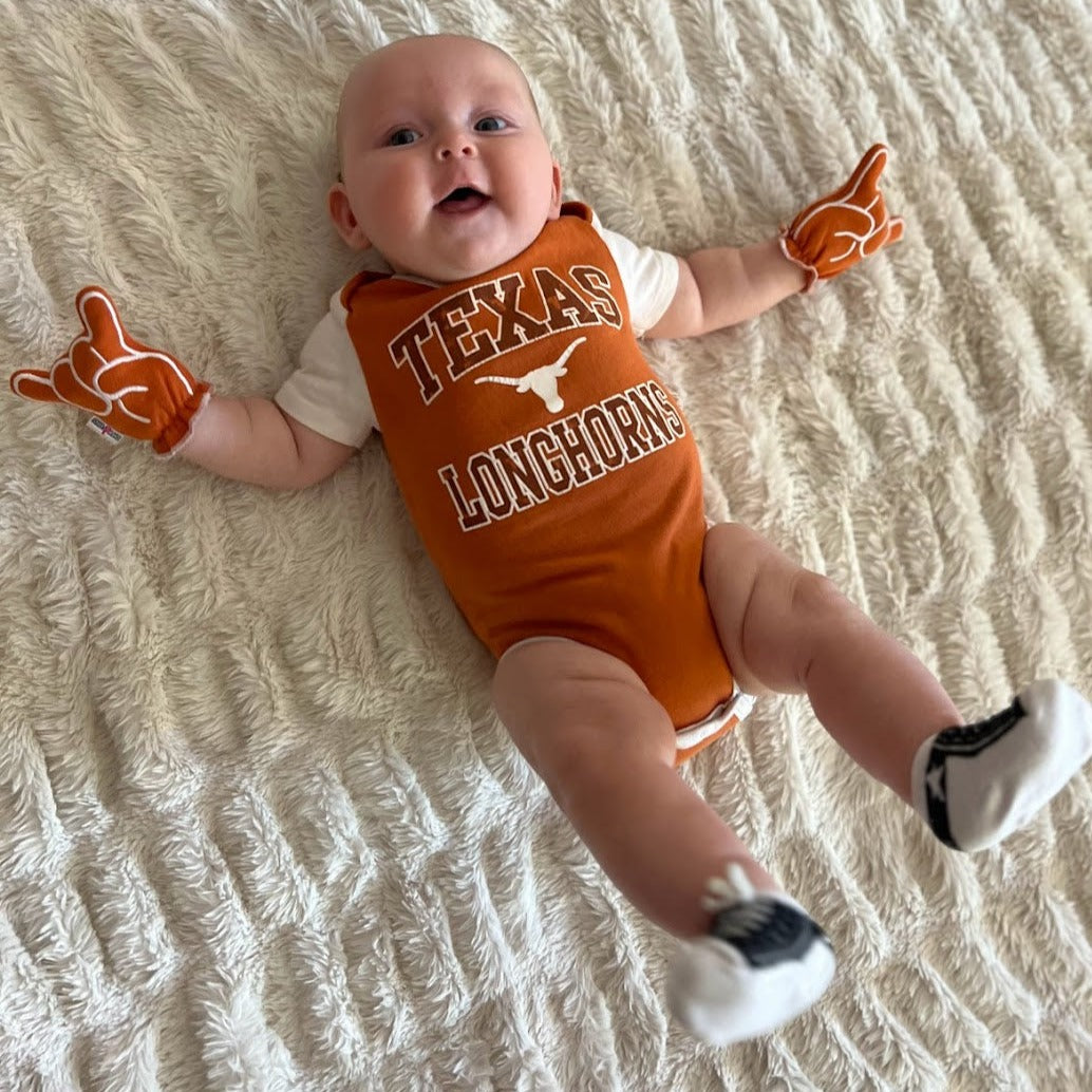 Newborn wearing UT Hook Em baby mittens in burnt orange