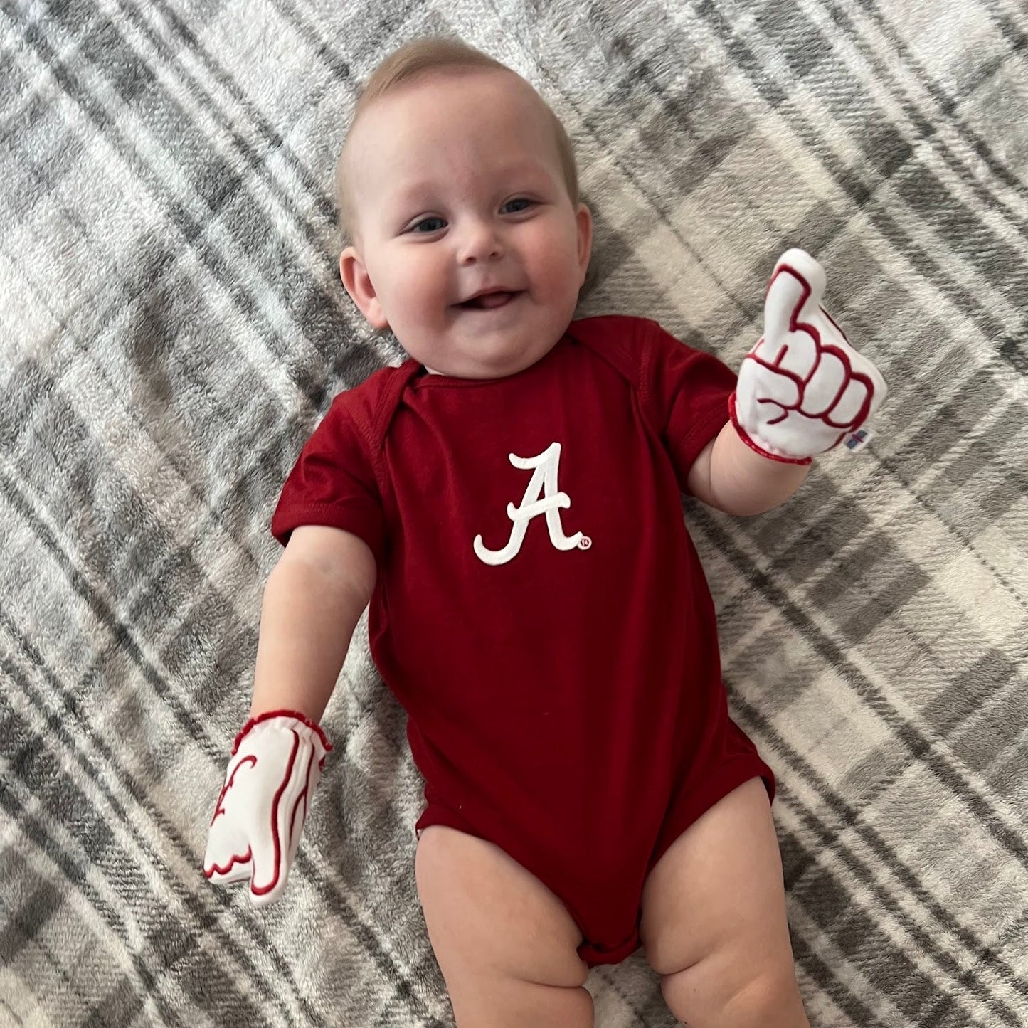 Infant wearing Alabama baby mittens in white