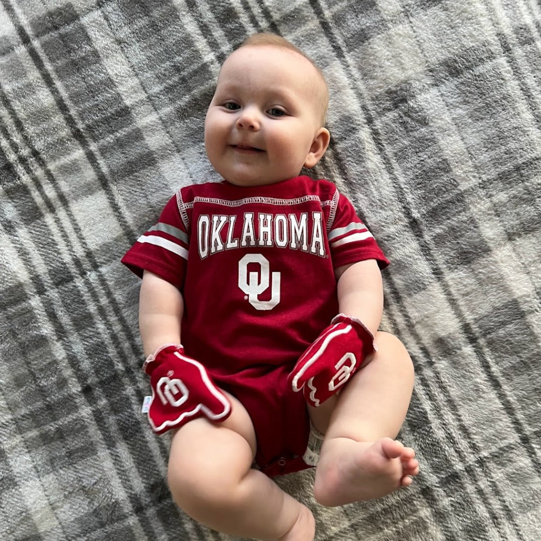 Infant wearing Oklahoma Boomer Sooner mittens in crimson