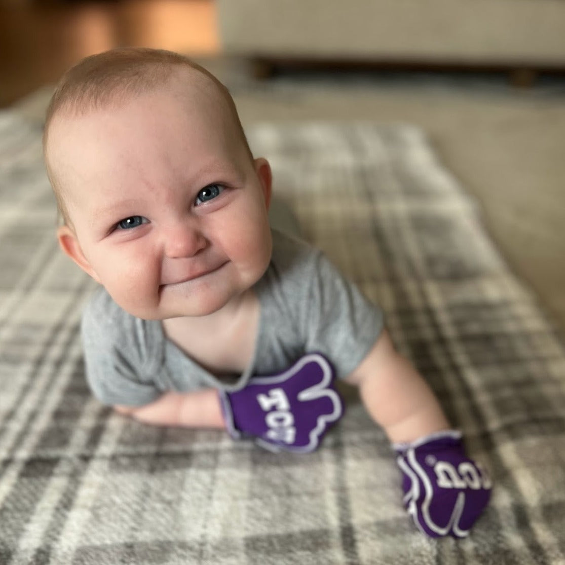 Infant wearing TCU Go Frogs baby mittens in purple